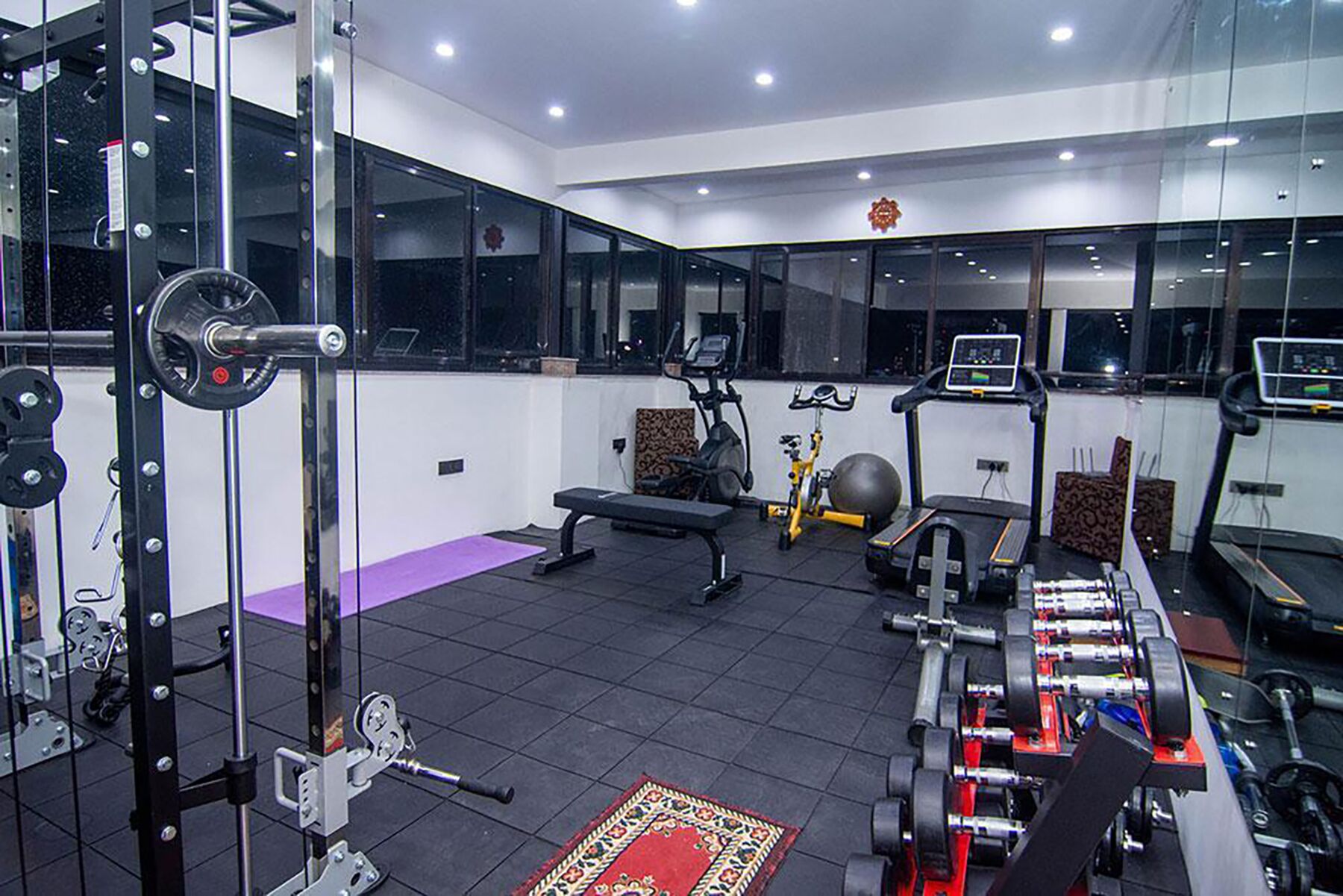 Un gimnasio con equipamiento de levantamiento de pesas, cintas de correr y pelotas de ejercicio.