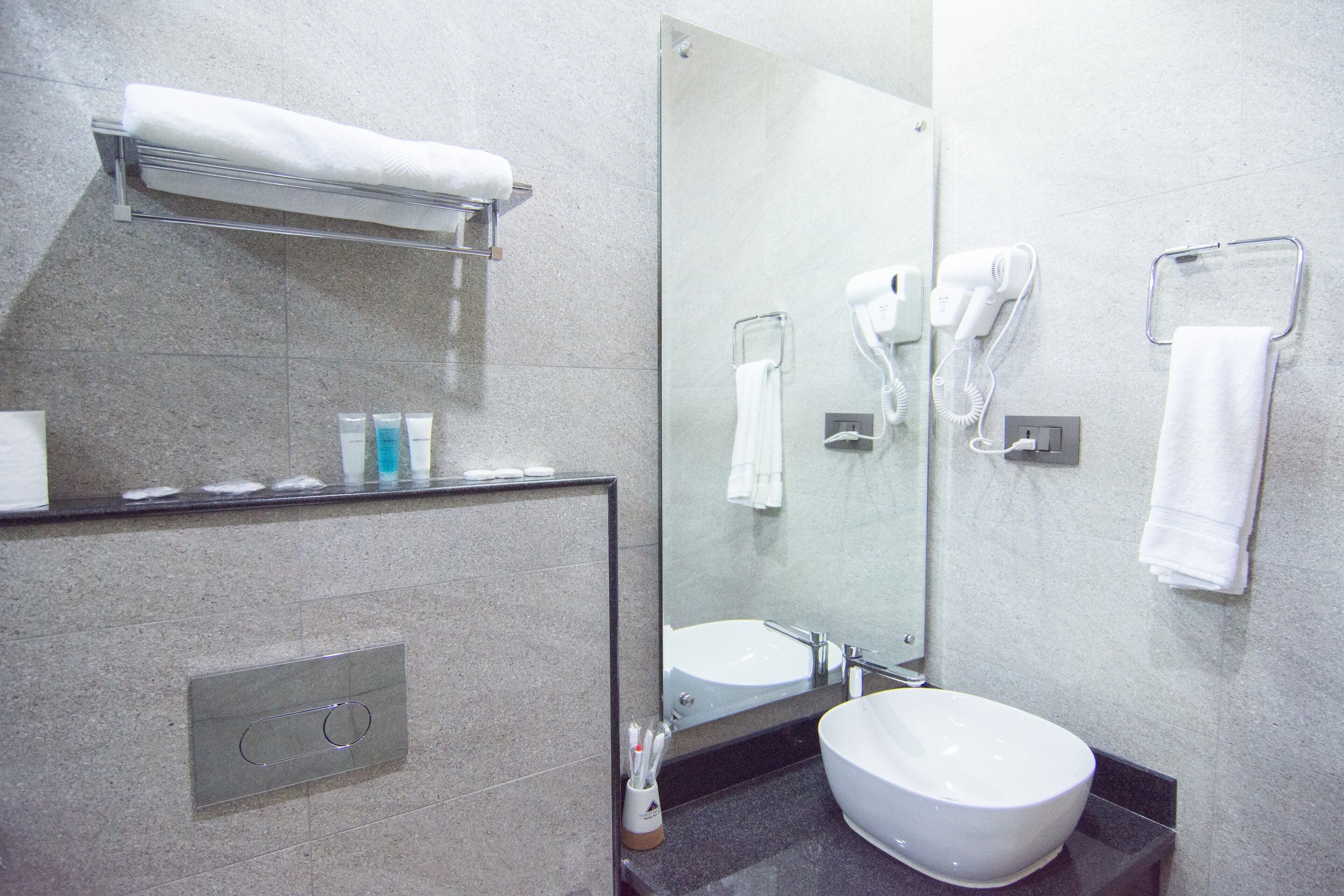 A modern bathroom with a large mirror, a sink, and a towel rack.