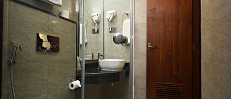 Un baño moderno con ducha de vidrio, una bañera blanca, un lavabo y una puerta de madera.