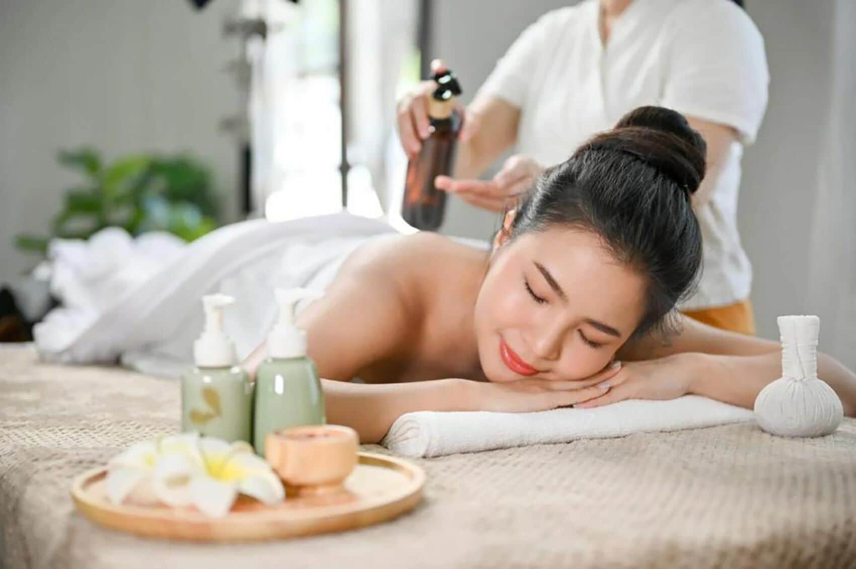 Een spa-omgeving met een massagetafel, flesjes massageolie en een aromadifuser.