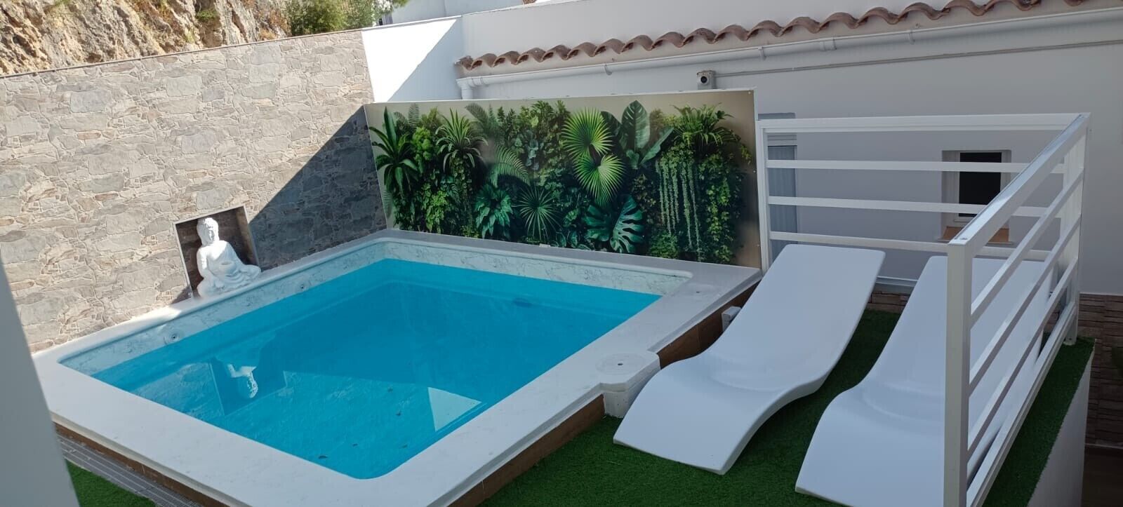 A swimming pool with a white deck, a white fence, and a mural of tropical plants.