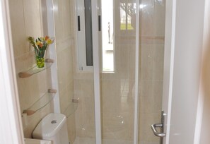 A bathroom with a toilet, a glass shower enclosure, and a shelf with a vase of flowers. - Villa with Private Pool, Terrace, A/C and Wi-Fi (San Miguel de Salinas)