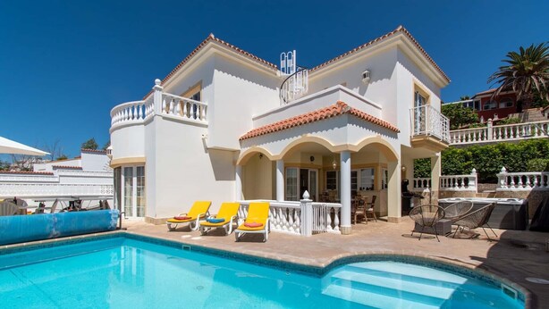 A two-story building with a swimming pool, outdoor seating, and a balcony. - Pet-Friendly Villa Encantada with Sea View & Pool (Arona)