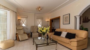 A living room with a glass coffee table, beige sofa, and a vase of flowers. - Pet-Friendly Villa Encantada with Sea View & Pool (Arona)