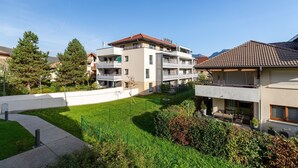 A residential area with modern buildings, a well-maintained lawn, and a clear sky. - 'Grand Studio by the Lake' with Mountain Views, Terrace and Wi-Fi. (Saint-Jorioz)