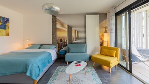 A modern hotel room with a bed, a sofa, a small table, and a balcony with a view. - 'Grand Studio by the Lake' with Mountain Views, Terrace and Wi-Fi. (Saint-Jorioz)