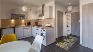 A compact kitchen with a washing machine, a microwave, and a coffee maker. - 'Grand Studio by the Lake' with Mountain Views, Terrace and Wi-Fi. (Saint-Jorioz)