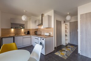 A compact kitchen with a washing machine, a microwave, and a coffee maker.