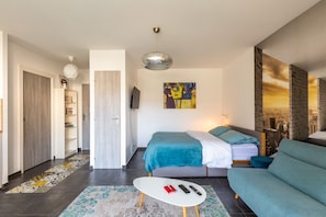 Une chambre moderne avec un lit, un canapé et une petite table sur laquelle sont posées des télécommandes.