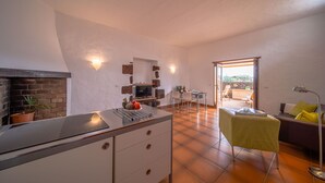 Een moderne keuken met een inbouwfornuis, een eethoek met tafel en stoelen, en uitzicht op het buitenterras.