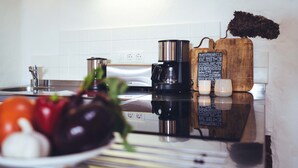 Een keuken met een fornuis, koffiezetapparaat en een houten snijplank met tekst.