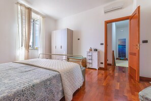 A bedroom with a bed, wardrobe, dresser, and a view of a room with a painting.