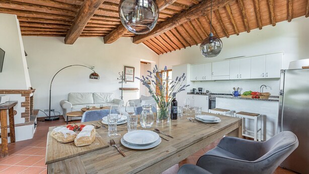 A dining area with a wooden table set for a meal, a sofa, and a kitchen in the background. - Lavanda, Montebuoni, Gaiole in Chianti, Siena and Chianti (Gaiole in Chianti)
