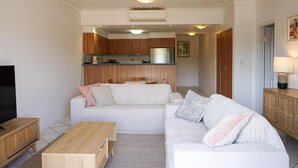 Ein modernes Wohnzimmer mit einem weißen Sofa, einem Holztisch und einem Fernseher.
