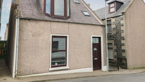A two-story house with a stone facade, a bay window, and a chimney. - Rockstar Cottage (Macduff)