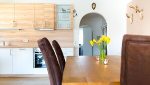 A modern kitchen with wooden cabinets, a built-in oven, and a dining area with a wooden table and chairs.