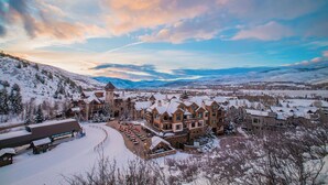 A snow-covered resort with multiple buildings, a central tower, and a ski lift area.