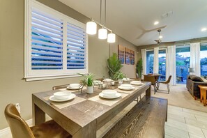 Un comedor con una larga mesa de madera dispuesta para seis comensales, rodeada de sillas, y vistas al exterior a través de amplios ventanales.