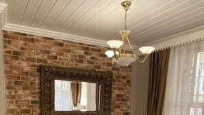Une chambre d’hôtel avec un mur en briques, un grand lit avec une literie blanche, des coussins dorés et un lustre.