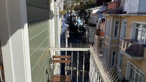 Un balcon étroit doté d’un sol à motifs, d’un banc en bois et d’une balustrade blanche.