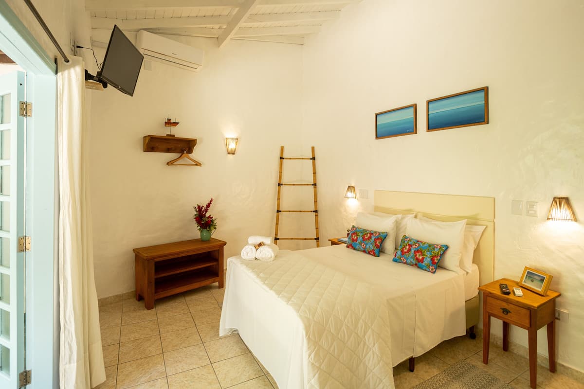 Un dormitorio con cama, mesita de noche, lámpara y televisión montada en la pared.