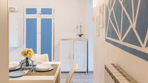 Una cocina moderna con armarios blancos, una mesa de comedor lista con platos, y un diseño geométrico azul en la pared.