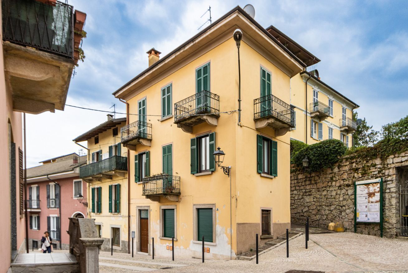 A multi-story building with balconies, a stone wall, and a cobblestone street.