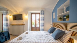 Un dormitorio con una cama, un televisor, una ventana y una pared azul con estantes.
