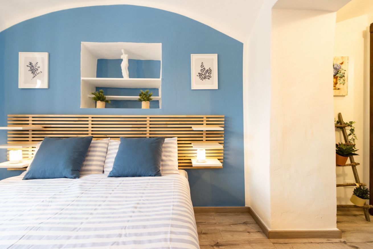 Ein Schlafzimmer mit einem Bett, Nachttischen, einer Kopfteil, Wandbildern und einem Regal.