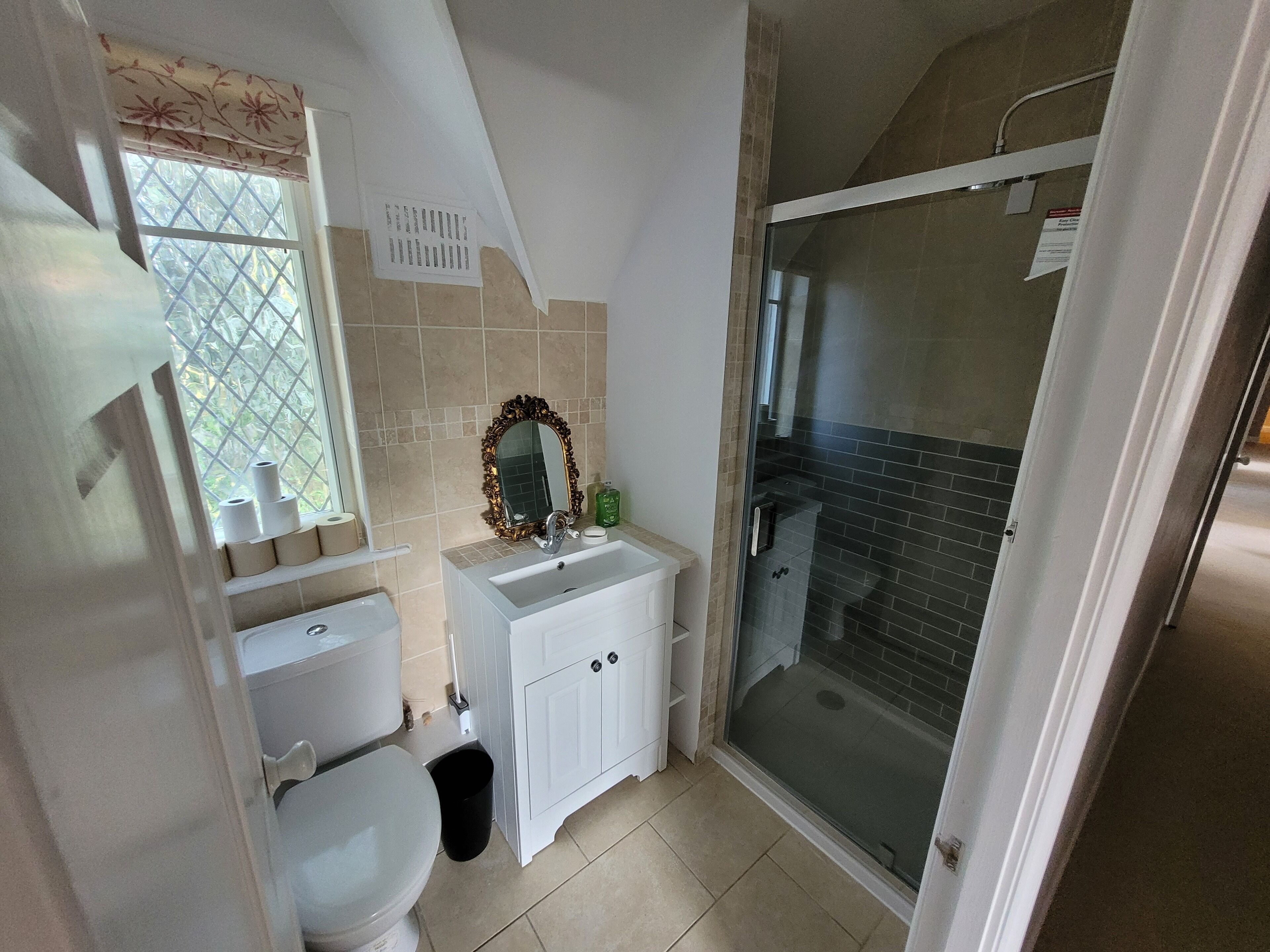 Un bagno con WC, lavandino, specchio e doccia.