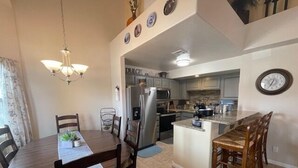 A compact kitchen with a central island, a dining area with a chandelier, and a clock on the wall. - Desert Ridge Retreat by Mesquite Vacation Rentals with Pet Friendly Amenities and $510 in free daily activities (Mesquite)