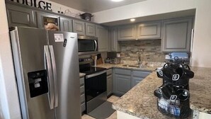 A modern kitchen with stainless steel appliances, granite countertops, and a stone backsplash. - Desert Ridge Retreat by Mesquite Vacation Rentals with Pet Friendly Amenities and $510 in free daily activities (Mesquite)
