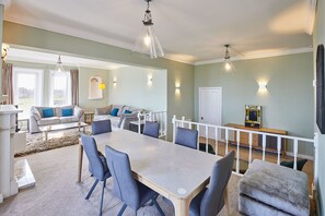 A spacious living room with a large dining table, comfortable seating, and a view of the outdoors.