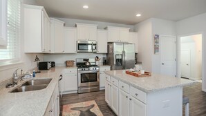 Una cucina moderna con mobili bianchi, elettrodomestici in acciaio inossidabile, piani in granito e un tappeto decorato.