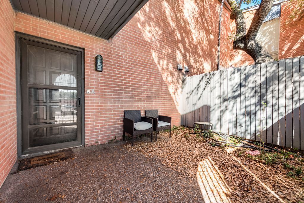 Un bâtiment en briques avec une porte, deux chaises et une petite table.