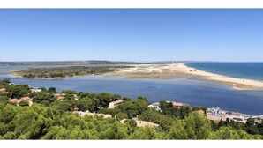 A coastal landscape with a beach, clear blue sky, and residential buildings in the foreground. - Chez Nicolle et Jean - House near Narbonne (Canet)