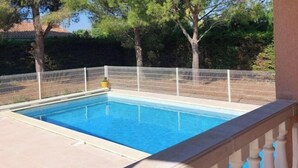 A rectangular swimming pool with a white fence and balustrade, surrounded by trees and a clear blue sky. - Chez Nicolle et Jean - House near Narbonne (Canet)
