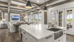 A spacious kitchen with a large island, pendant lighting, and a view to the outdoors. - Dune Lake Escape with Pool and Elevator (Santa Rosa Beach)