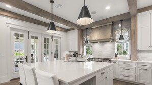 A spacious kitchen with a large island, white cabinetry, and pendant lighting. - Dune Lake Escape with Pool and Elevator (Santa Rosa Beach)