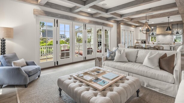 A spacious living room with a large window, a sofa, a coffee table, and a dining area. - Dune Lake Escape with Pool and Elevator (Santa Rosa Beach)