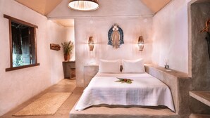 Een slaapkamer met een groot bed, een hanglamp en een decoratief object aan de muur.