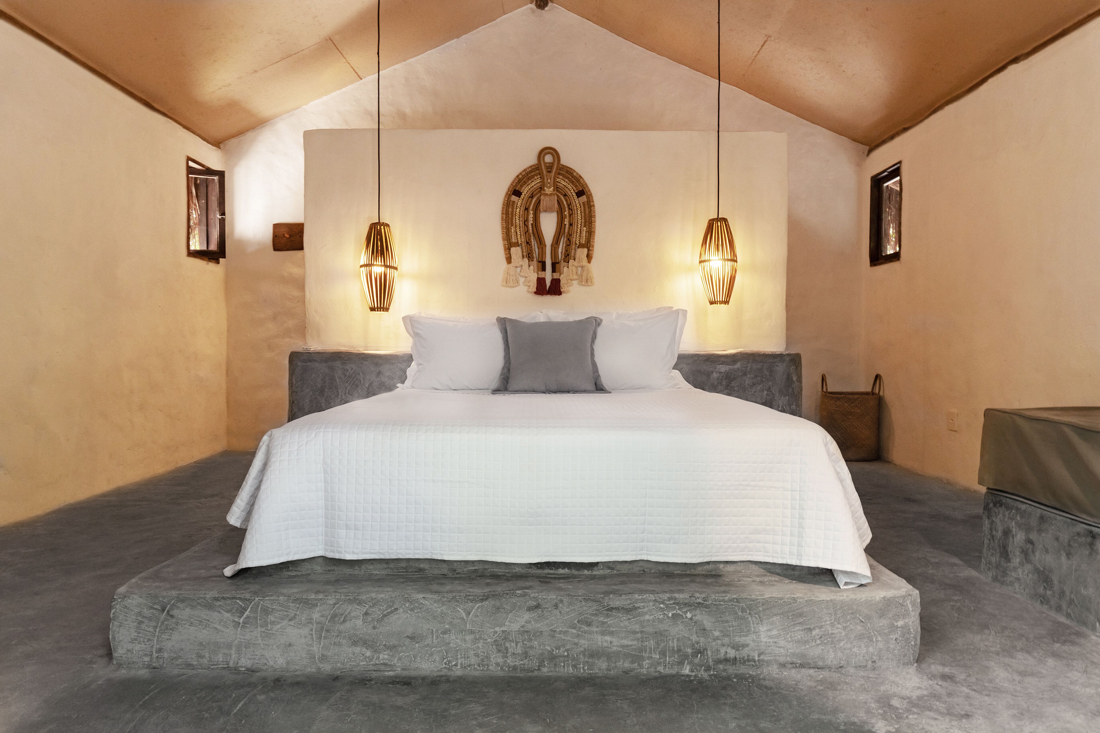 A bedroom with a large bed, a decorative wall hanging, and two wall-mounted lamps.