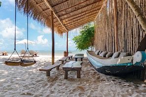 A beach setting with thatched-roof structures, wooden benches, and a boat-shaped seating area. - Ventos Moreré Hotel & Beach Club (Cairu)
