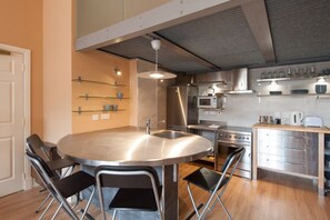 A modern kitchen with a central island, stainless steel appliances, and foldable chairs. - Royal Mile Mansions by Edinburgh City Apartments (Edinburgh)