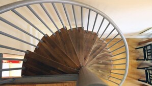 A spiral staircase with a wooden handrail and metal balusters. - Royal Mile Mansions by Edinburgh City Apartments (Edinburgh)