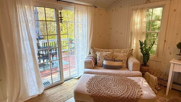 Een gezellige slaapkamer met een groot bed, een bank en een eethoek, zichtbaar door de schuifdeur met glas.