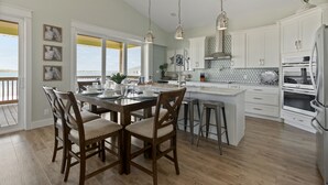 A spacious kitchen with a large island, white cabinetry, and pendant lighting. - Private home with sweeping water views, 2 min walk to the beach.  Sleeps 13! (Navarre)