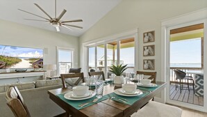 A dining area with a view of the beach, a ceiling fan, and a large window. - Private home with sweeping water views, 2 min walk to the beach.  Sleeps 13! (Navarre)
