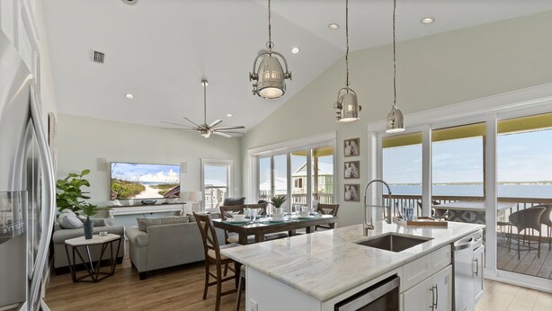 A spacious kitchen with a large island, a dining area with a view, and a balcony with outdoor seating. - Private home with sweeping water views, 2 min walk to the beach.  Sleeps 13! (Navarre)