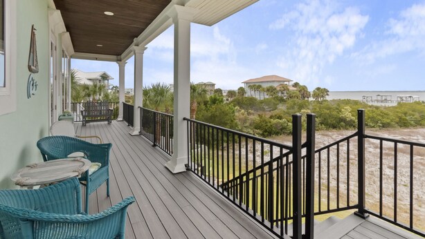 A covered outdoor area with wicker chairs and a wooden deck. - 🌊 Narrvelous – Sound-View 5BR Home w/ Pool, Tennis, Firepit & Walk to Beach (Navarre)